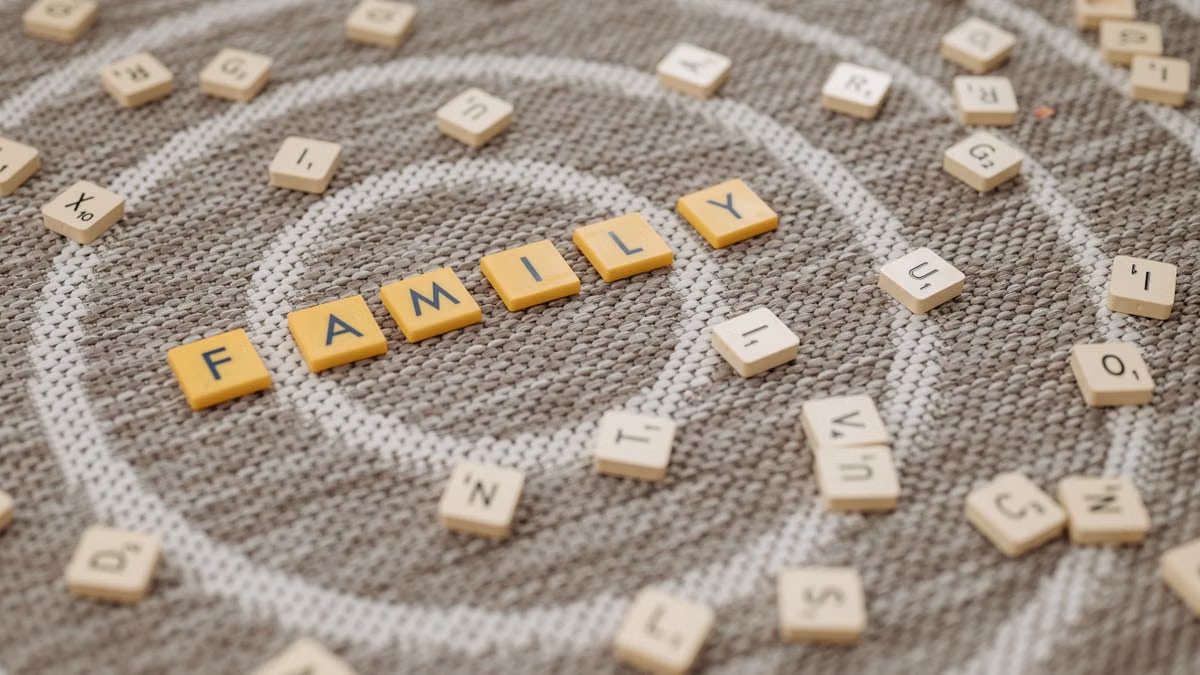 An artistic display of Scrabble tiles spelling 'FAMILY' on a textured carpet surface.